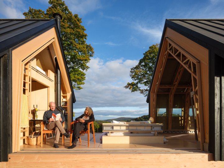Couple relaxing together inside an open Cabin ANNA overlooking the Vermont landscape