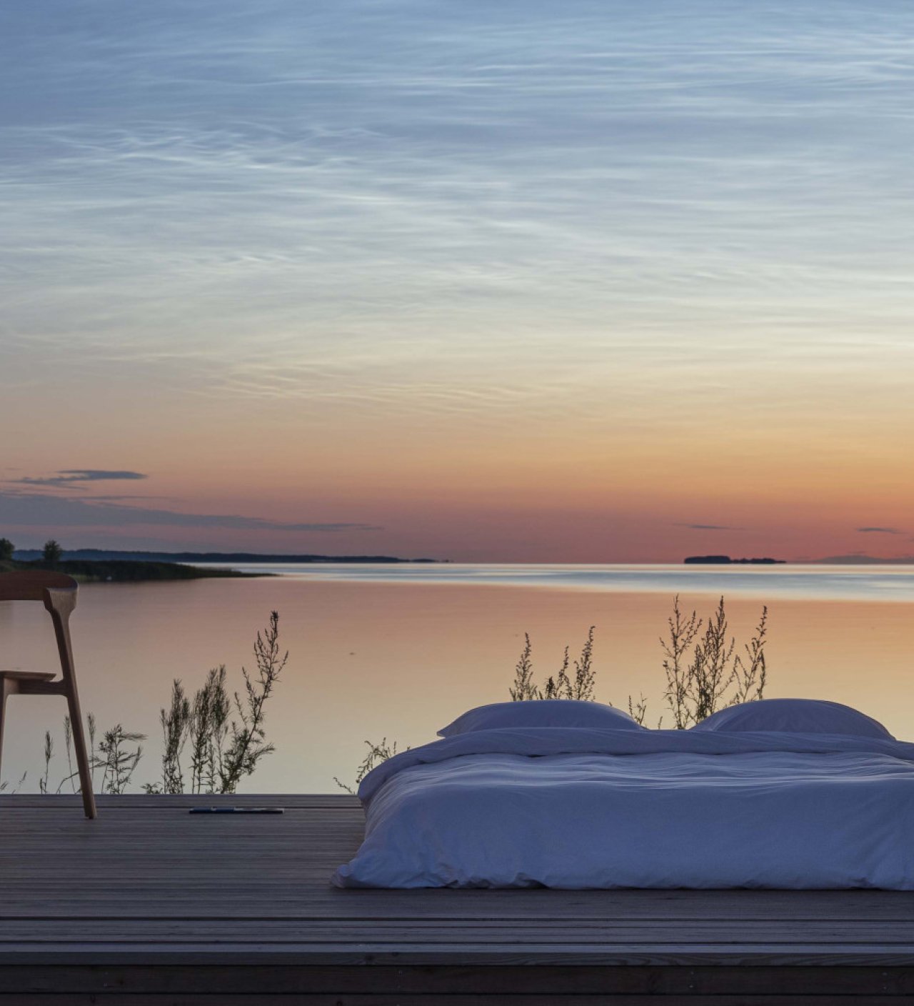 Cabin ANNA opened to a waterfront landscape at sunset, with a bed overlooking the water